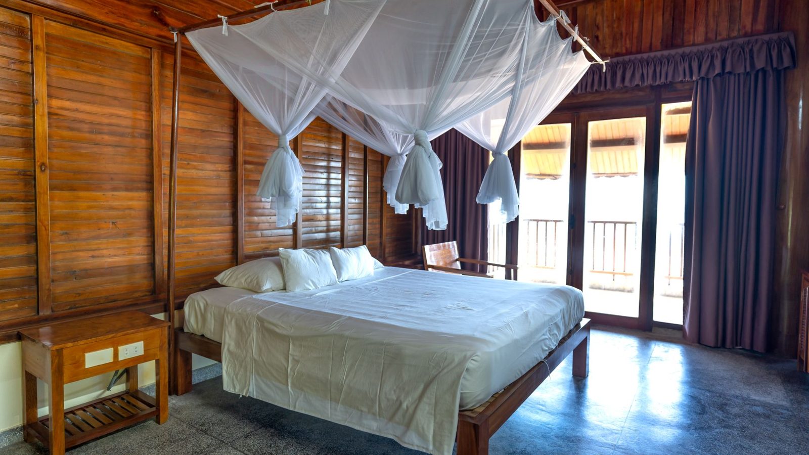 Elegant wooden cabin bedroom with canopy bed and natural lighting.